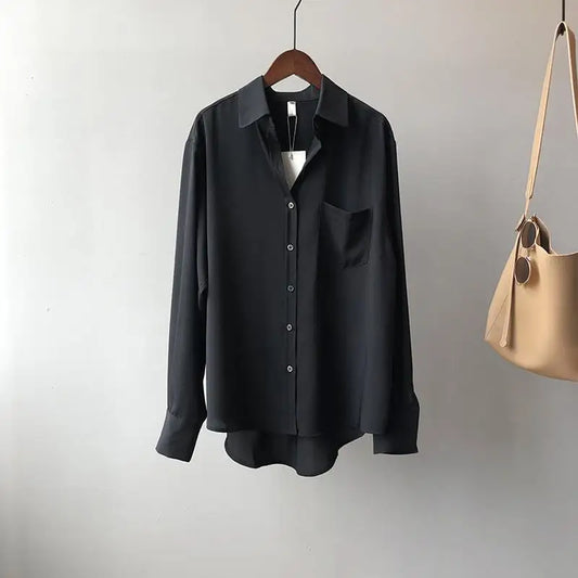 Black shirt on a hanger with a beige handbag on a gray background