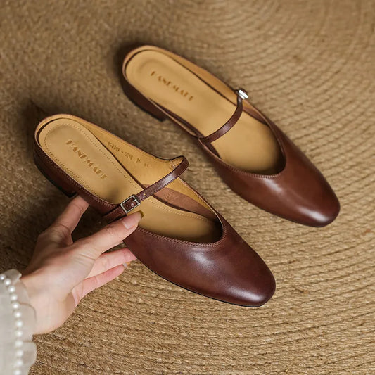 Pair of brown leather shoes with a strap on a textured surface