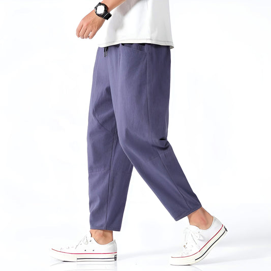 Person wearing purple pants and white sneakers on a white background
